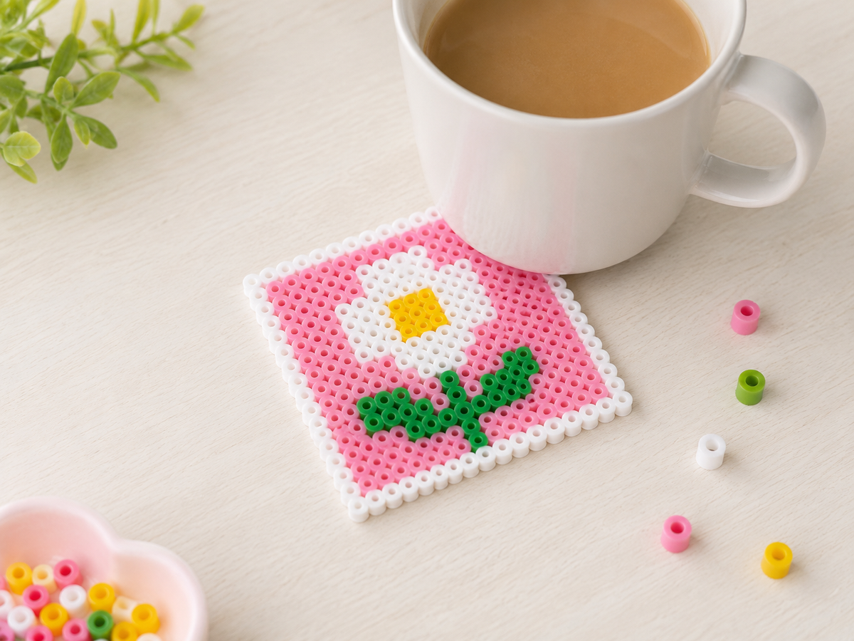 Flower fuse bead coaster with a coffee mug on a light tabletop